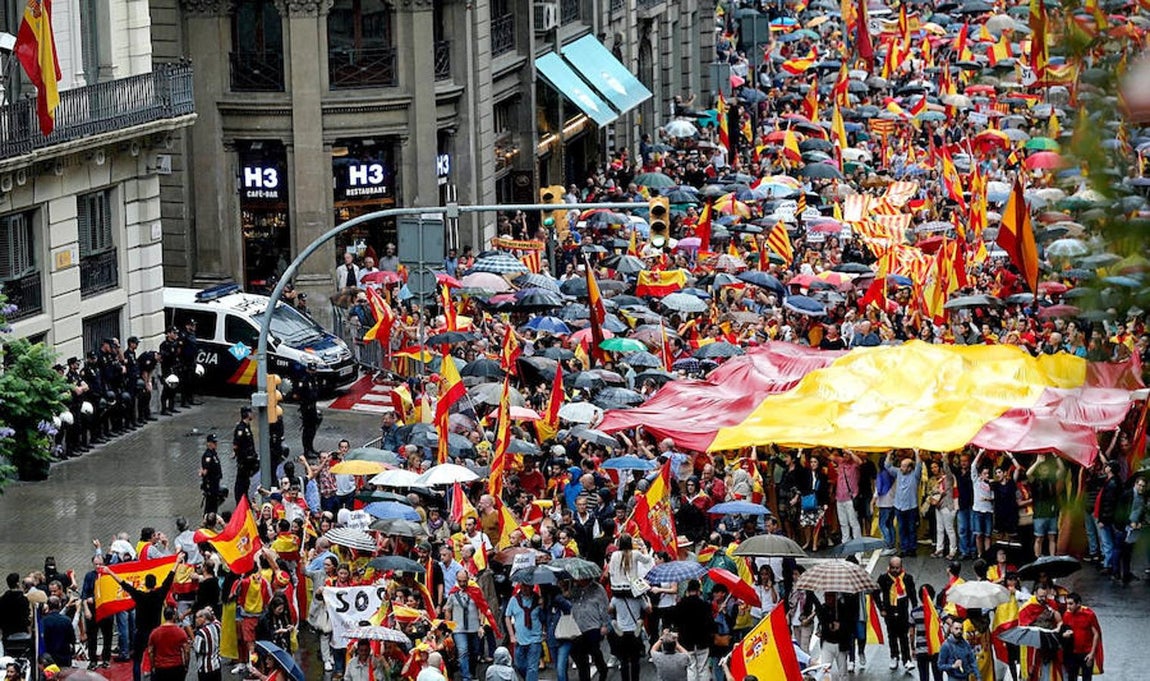 La manifestación convocada por Movimiento Cívico de España y Catalanes, a su paso por la Jefatura Superior de Policía de Barcelona (izq), portando cientos de banderas españolas y catalanas, y con el lema «Catalunya es Espanya. Democracia, futuro y libertad».. 