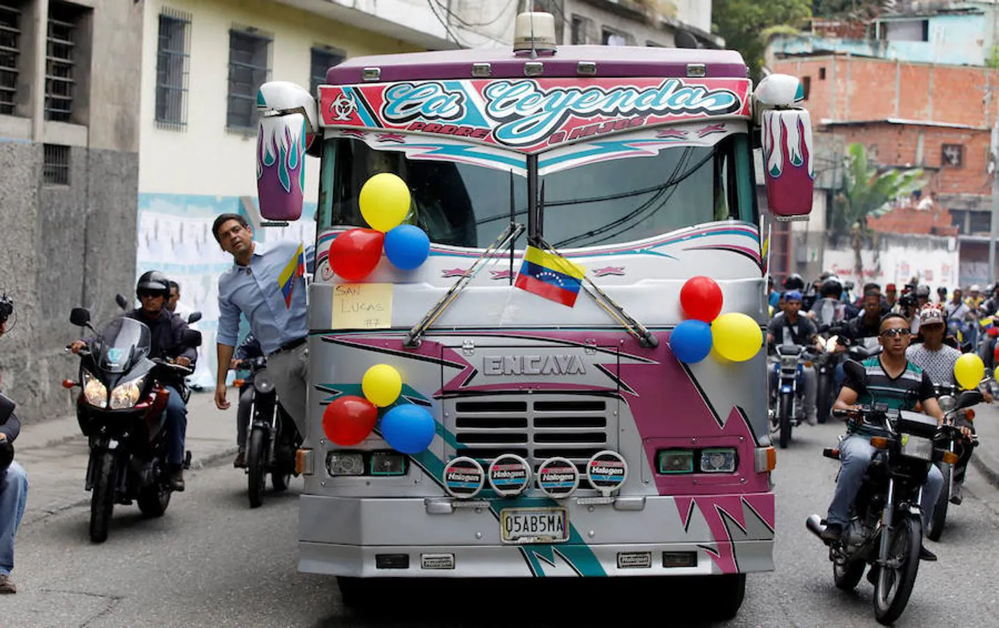 Carlos Ocariz, candidato por la MUD, llega al colegio electoral asomando el cuerpo por la puerta de un autobús. Reuters