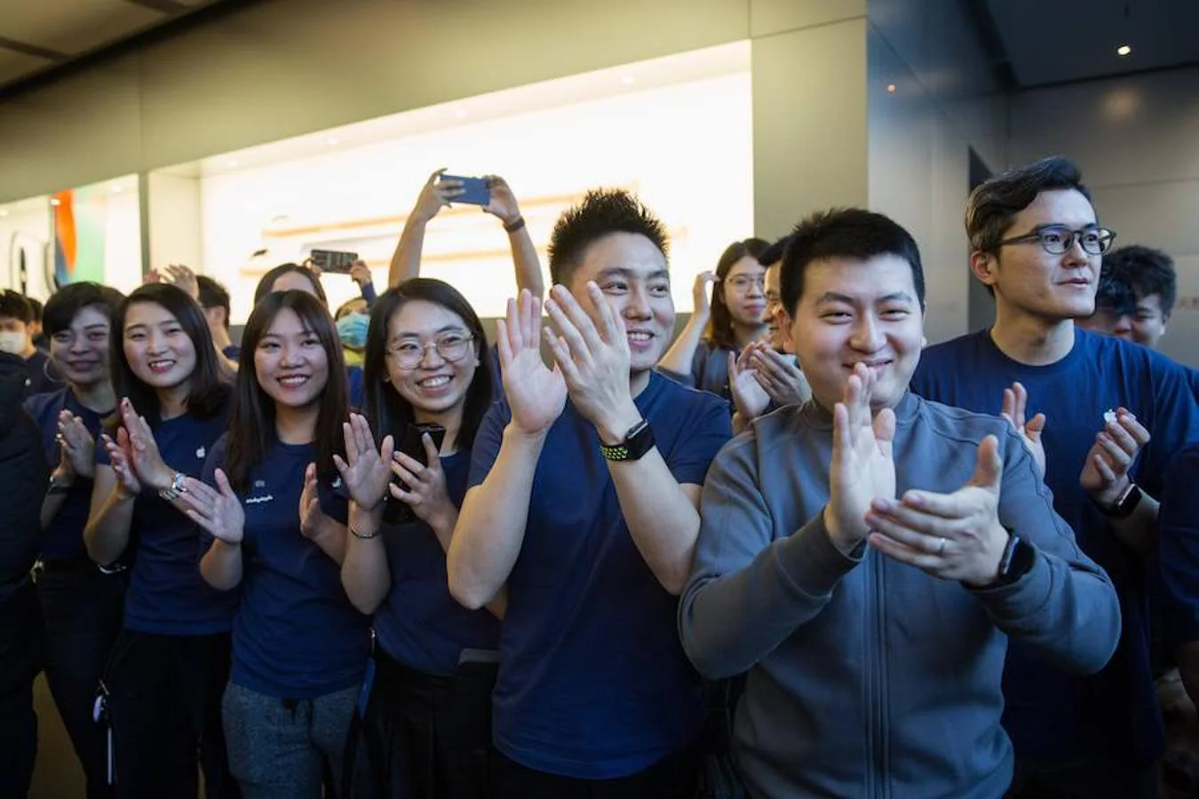Personal de la tienda Apple de Pekín aplaude a los clientes que entran. 