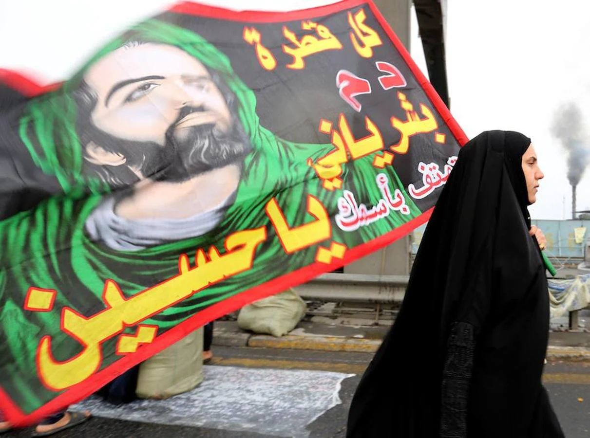 Una peregrina porta una bandera con la imagen del imán Husein. 