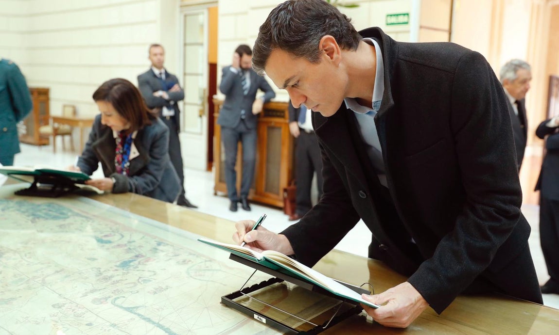 El líder socialista, Pedro Sánchez, firma en el libro de condolencias. También vemos a Margarita Robles, la portavoz del PSOE en el Congreso, de fondo. 