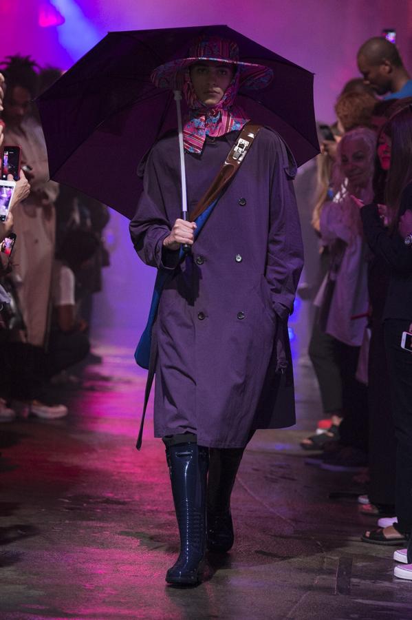 Raf Simons. Modelo del desfile primavera/ verano 2018 con gabardina y paraguas violeta.
