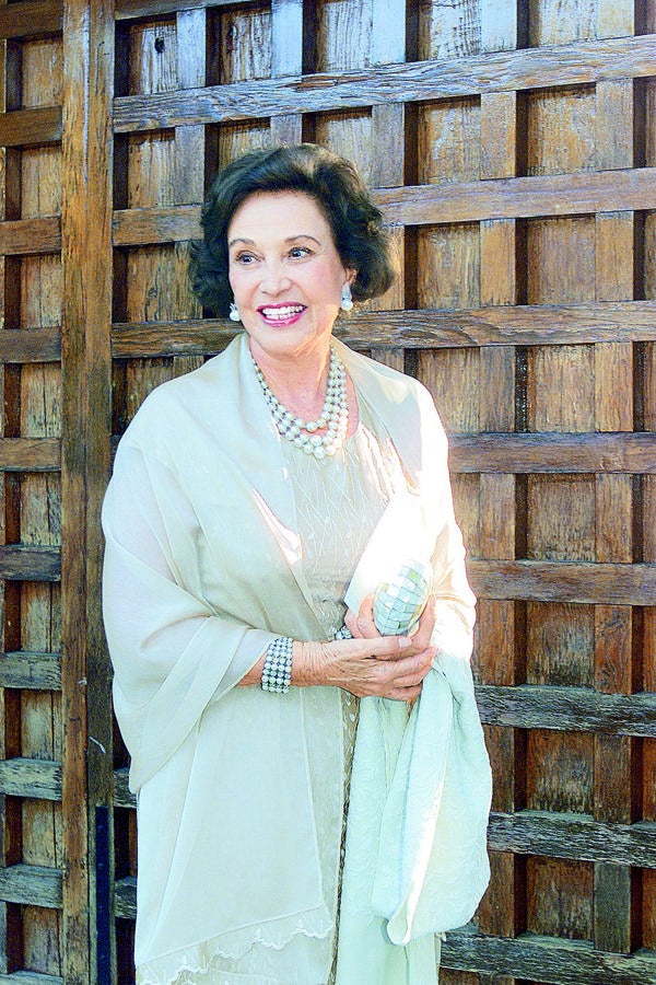 Carmen Franco posa junto a una puerta de madera antes de una boda. 