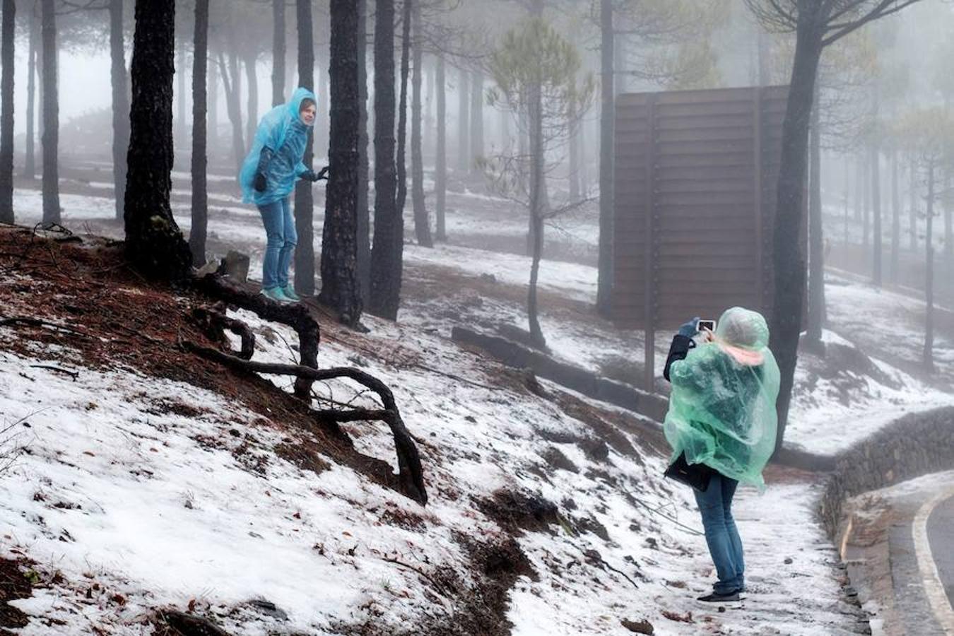 Dos personas se fotografían con el paisaje nevado como telón de fondo en Tejeda, en la provincia de Las Palmas de Gran Canaria.. 