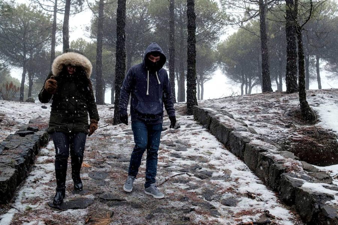 Dos personas caminan bajo precipitaciones en forma de nieve en Tejeda, en la provincia de Las Palmas de Gran Canaria.. 