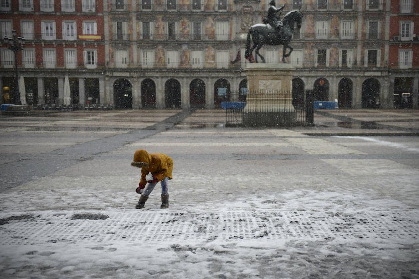 Una niña juega con la nieve en la Plaza Mayor de Madrid.. 