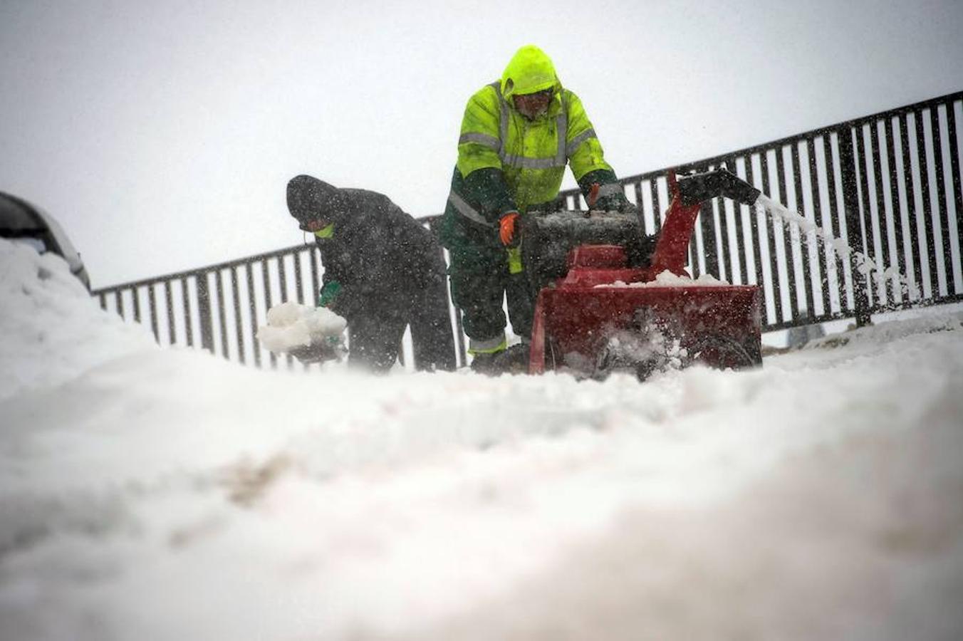 Dos hombres limpian una calle en la localidad cántabra de Reinosa, cuya comunidad se encuentra en alerta naranja por nieve que la Agencia Estatal de Meteorología (AEMET). 