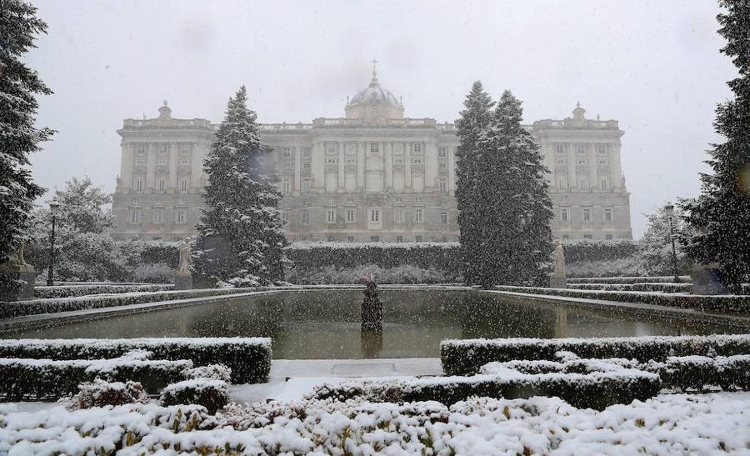 Vista del Palacio Real cubierto de nieve que cae desde primera hora de la mañana en la Comunidad de Madrid. 