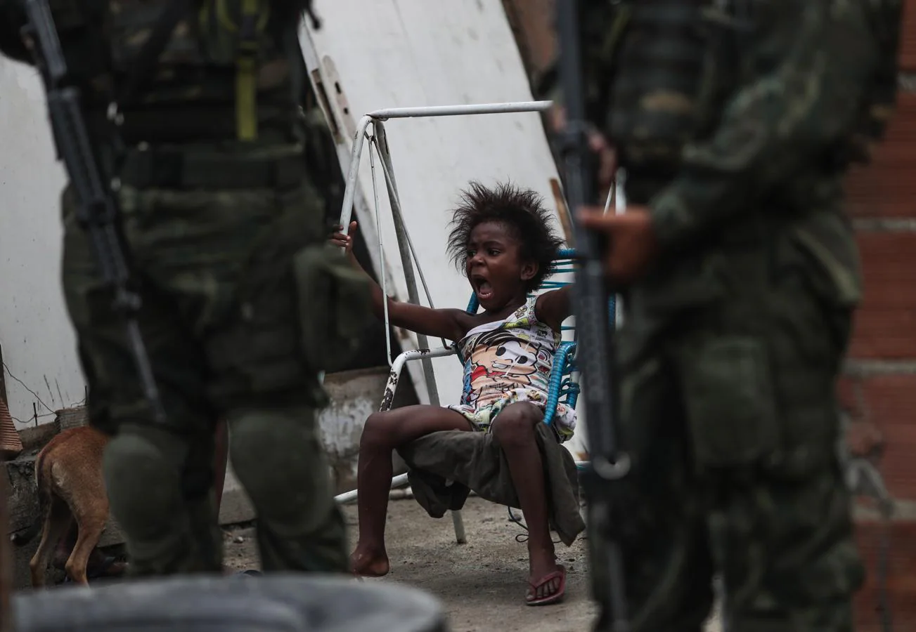 Un niño juega mientras las autoridades brasileñas participan en una operación. 