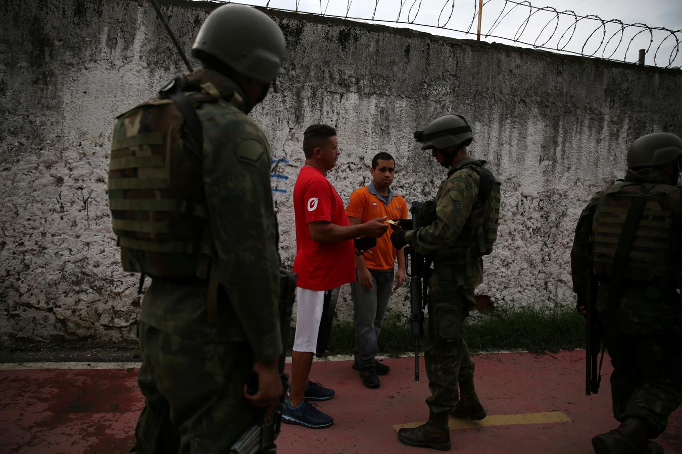 Los agentes revisan la documentación de los habitantes de la favela Kelson, en Río de Janeiro. 