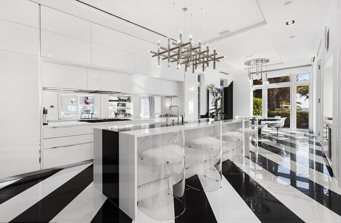 Cocina. En la isla principal destacan los muebles de Willy Rizzo y Aran Cucine y la lámpara de estilo años 70' de Robert Sonneman. En la habitación hay una zona de desayuno: este rincón lo preside una poderosa Elizabeth Taylor retratada por Vik Muniz, frente a ella, una mesa redonda en color negro hecha a medida por Willy Rizzo. A ésta la custodian seis sillas transparentes Vintage Laverne, de J.F. Chen