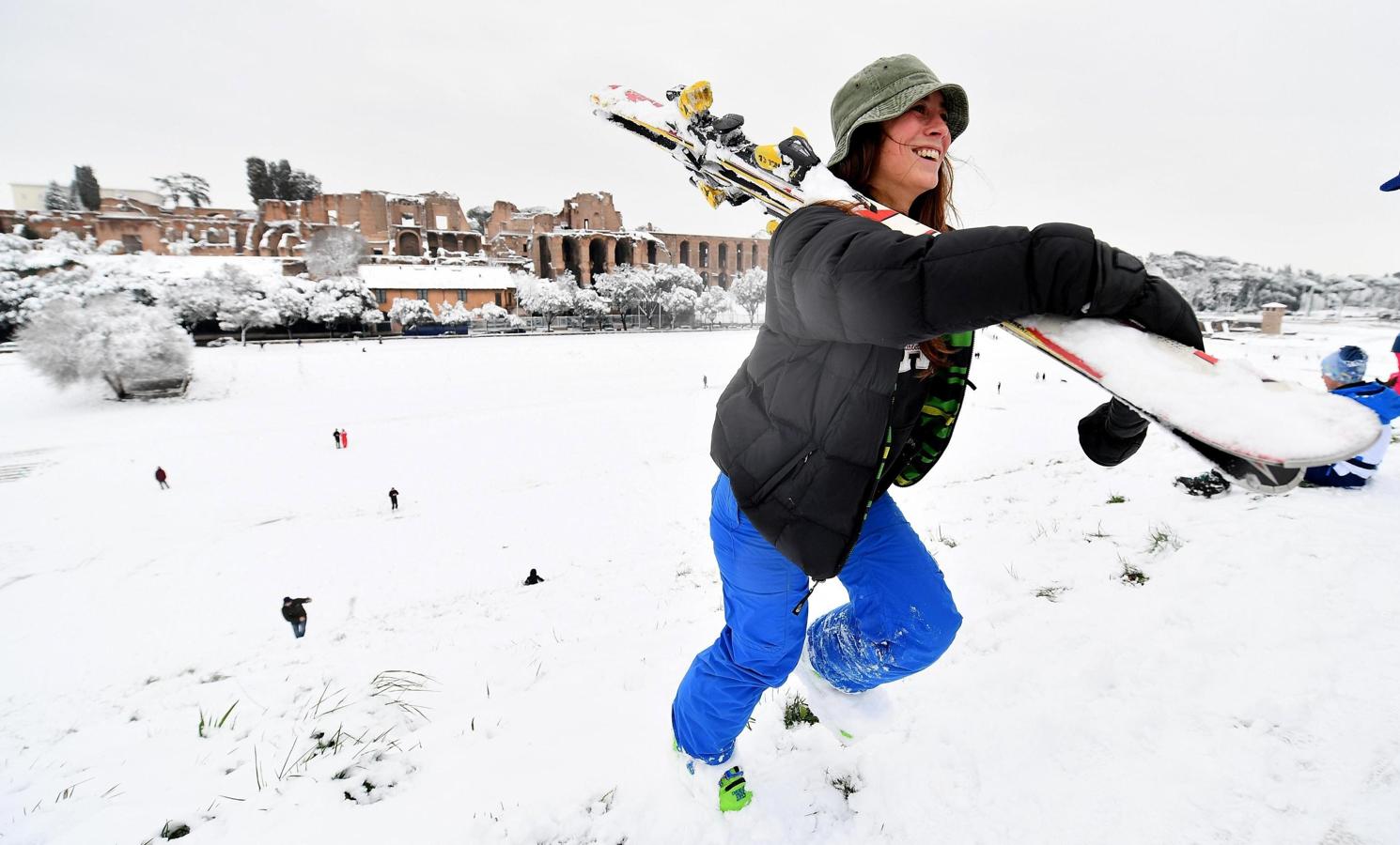 Una chica carga con sus esquís tras disfrutar de la nieve en el Circo Massimo en Roma. 