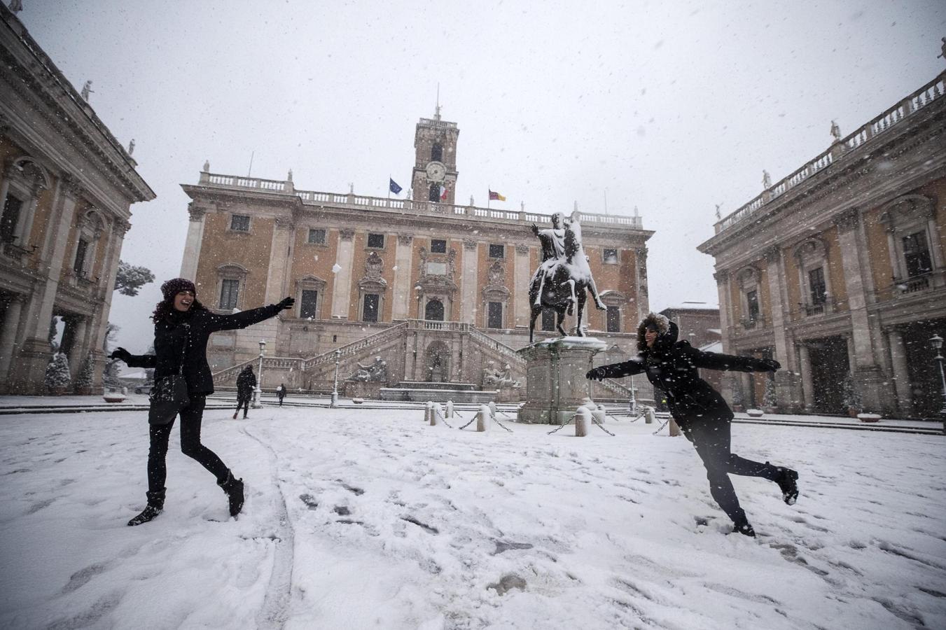 Dos chicas se lanzan bolas de nieve frente al Campidoglio durante una intensa nevada en Roma. 