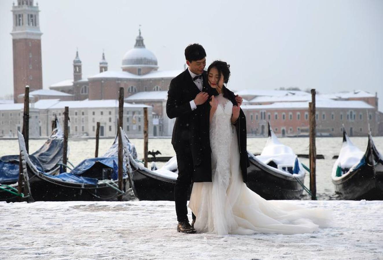 Una pareja de novios posa en la Plaza San Marcos de Venecia.. 