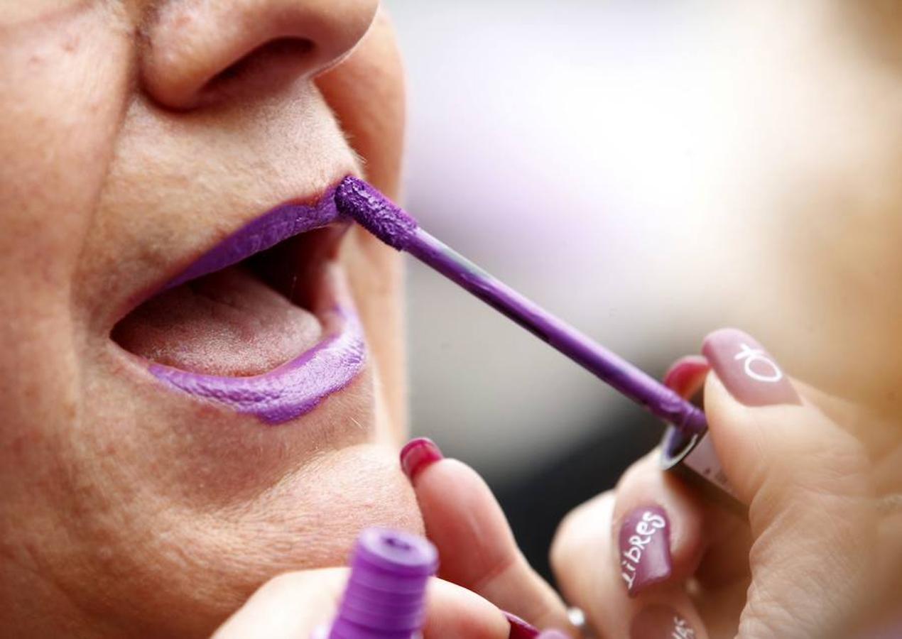 Una mujer se pinta los labios de violeta durante la concentración convocada por los sindicatos en la Plaza de la Cibeles, a las puertas del Ayuntamiento de Madrid, con motivo del Día Internacional de la Mujer.. 