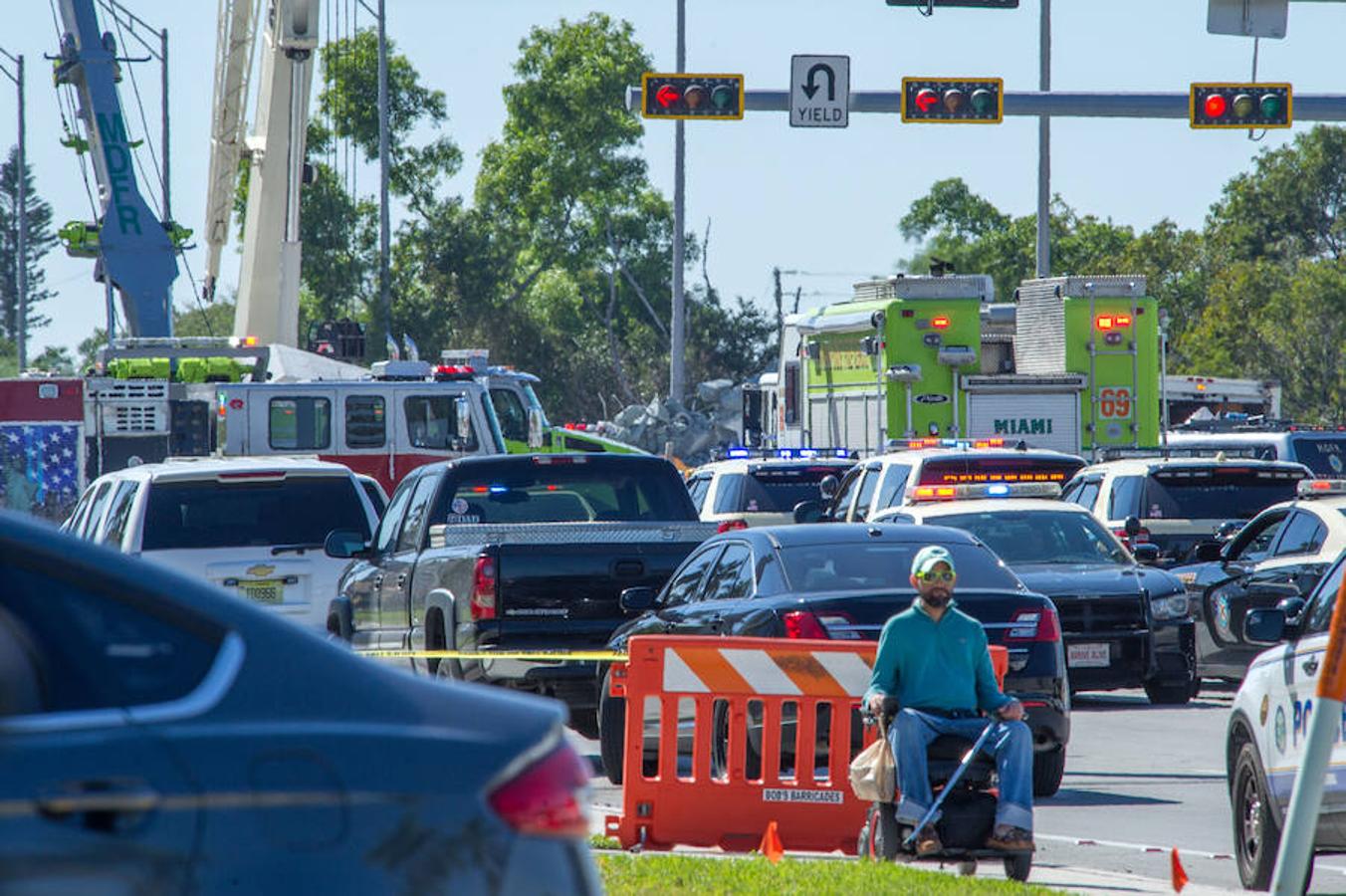 Una persona minusválida observa junto a decenas de vehículos de policía y bomberos que están atendiendo el accidente del puente para peatones que se ha derrumbado este jueves en las cercanías de la Universidad Internacional de Florida (FIU), en la ciudad estadonidense de Miami.. 