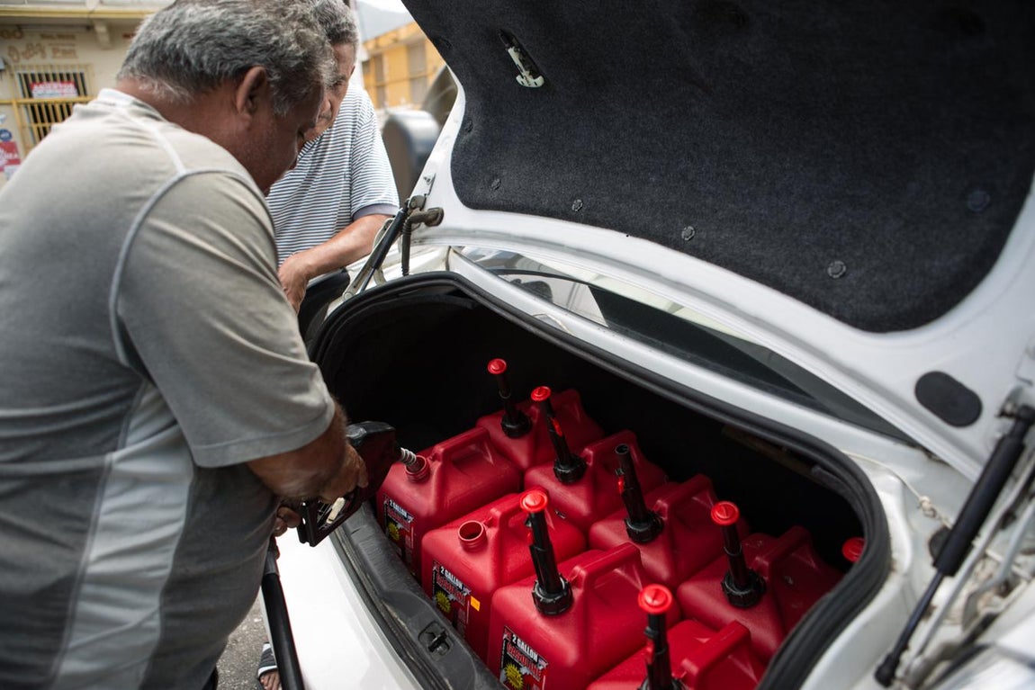 Un operario de la gasolinera en el centro de Yabucoa llena bidones para un vecino. En esta localidad, el 75% de sus 37.000 habitantes siguen sin electricidad seis meses después del huracán. Los generadores -que aquí llaman ‘plantitas’- son el modo de tener el mínimo suministro de luz para las necesidades más básicas. Pero su coste es muy alto: entre 300 y 400 dólares al mes solo por usarlo una ocho horas al día para conservar alimentos.. 