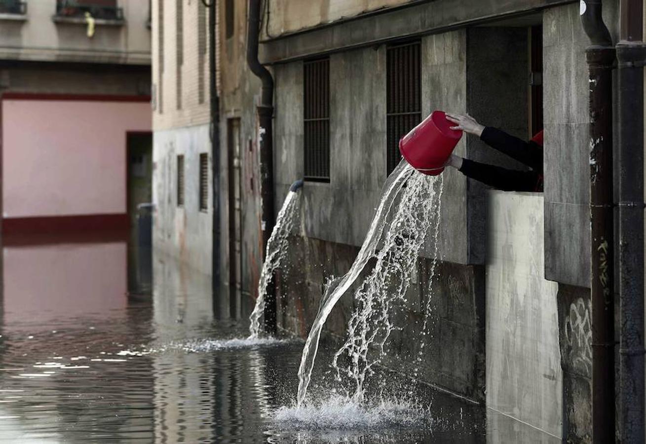 Una persona vierte el agua recogida que ha entrado en las cocinas de un restaurante de Tudela, tras la inundación que ha sufrido el casco viejo de la ciudad por la crecida del rio Ebro. 