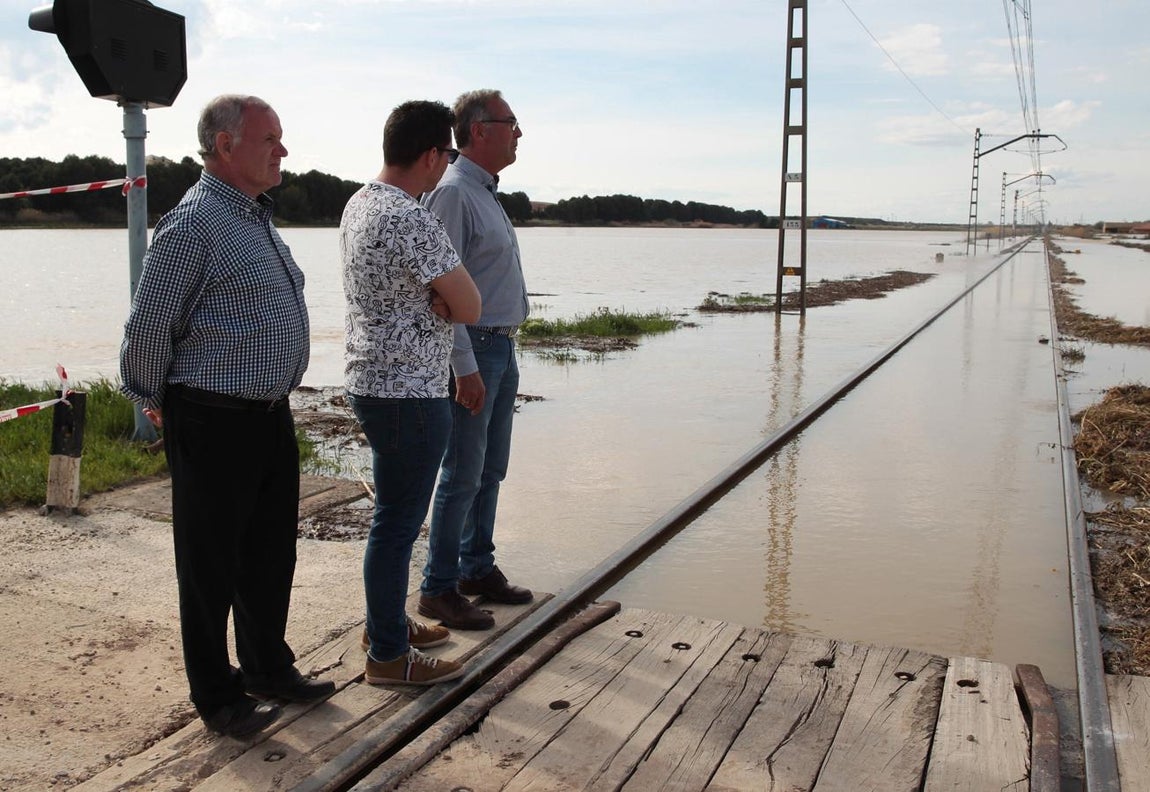El alcalde de Quinto de Ebro (Zaragoza), Jesús Morales (c), y dos concejales de la localidad contemplan la vía del tren de la línea Zaragoza-Barcelona, que ha tenido que ser cortada por motivos de seguridad al ser invadida por el agua del río Ebro. 