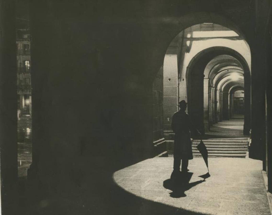 En la oscuridad, un hombre se refugia de la lluvia en los soportales de la Plaza Mayor (1951). 