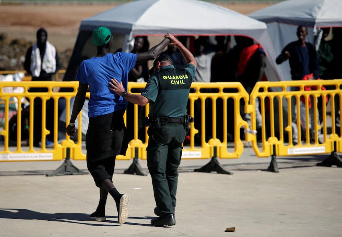 Uno de los guardias civiles –que cuida y vigila a las personas que llegan en patera a las costas de Cádiz y son trasladadas al pabellón «Antonio Gavira», en el municipio Los Barrios, cerca de Algeciras– aparta el brazo del inmigrante que se abrazaba a su cuello.. 