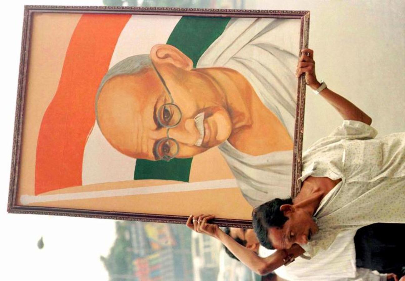 Un hombre porta el retrato de Gandhi en el 50 aniversario de la independencia de la India. 