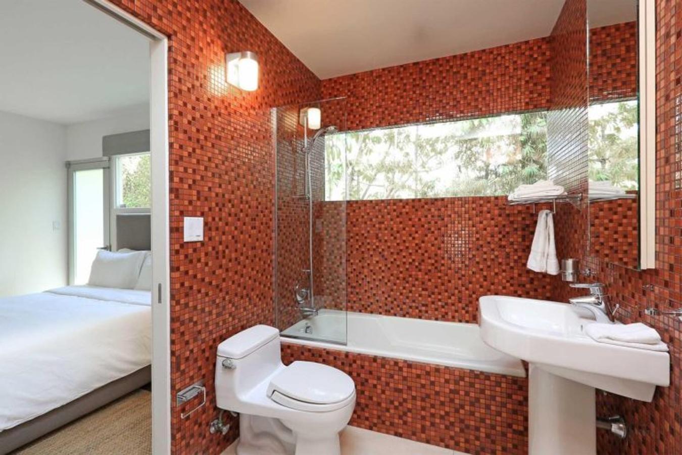 Cuarto de baño. El dormitorio de invitados tiene también cuarto de baño privado. Es sencillo pero funcional, y también está revestido de azulejos, esta vez en rojo