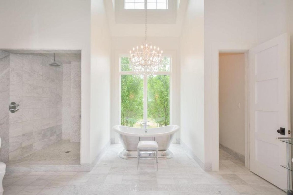 Cuarto de baño. Las líneas minimalistas se marcan claramente en el baño, donde la protagonista es una lujosa bañera exenta sobre la que cae una lámpara de araña