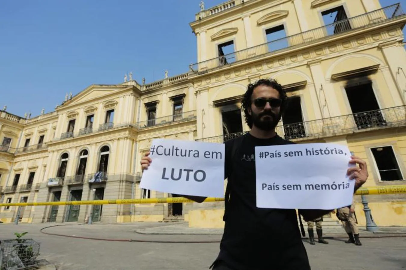 Un hombre muestra un cartel en el que se lee «Cultura en luto» frente al Museo Nacional de Río de Janeiro