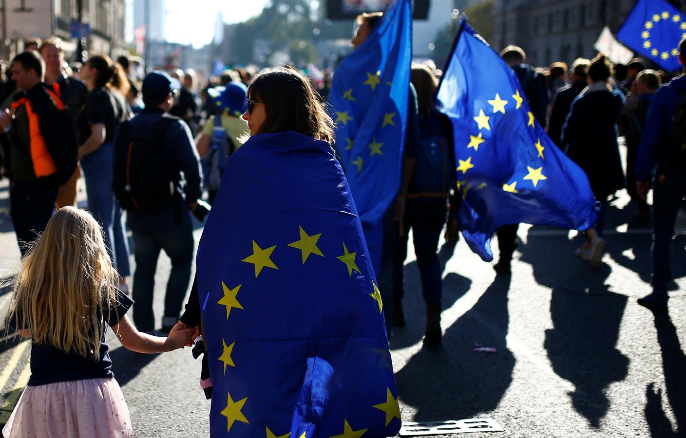 Una joven, con la bandera de la Unión Europea a su espalda. 