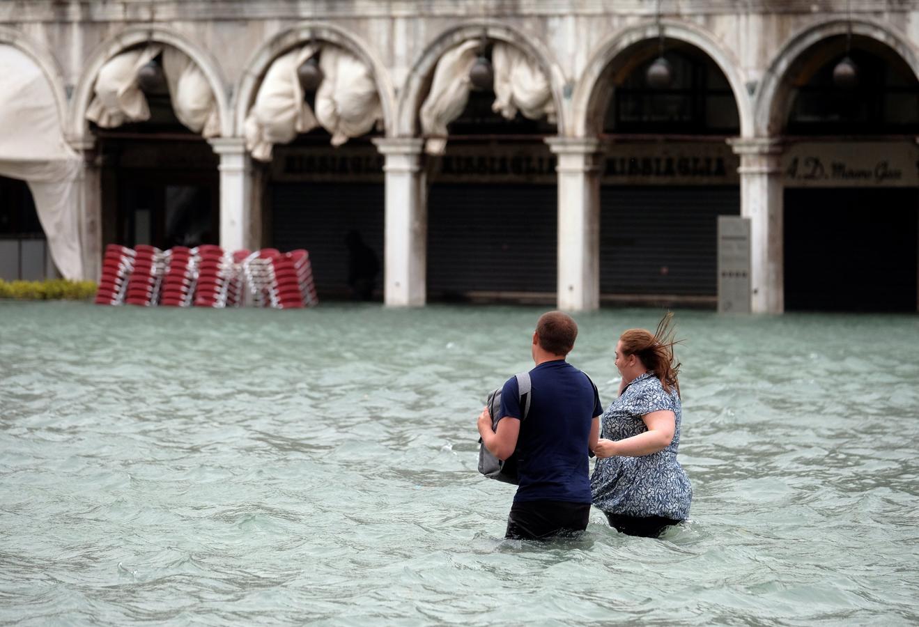 Dos turistas tratan de cruzar la Plaza de San Marcos, en Venecia, que se encuentra totalmente inundada.. 