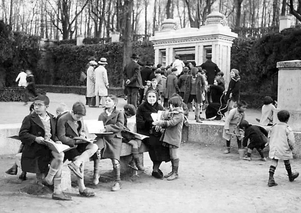 13.. 30 de noviembre de 1929. Un grupo de escolares lee los libros de una biblioteca infantil instalada dentro del parque