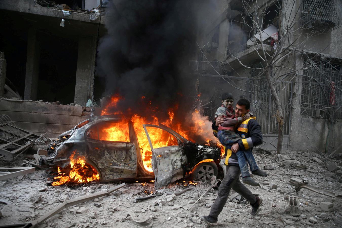 Un miembro de la Defensa Civil de Siria transporta a un niño herido en la ciudad sitiada de Hamoria, Ghouta Oriental, en Damasco (Siria), el 6 de enero de 2018.. 