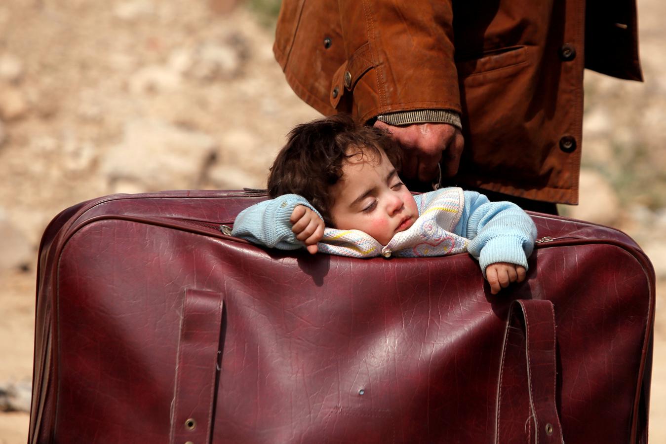 Un niño duerme en una maleta en el pueblo de Beit Sawa, en el este de Ghouta, Siria, el 15 de marzo de 2018.. 