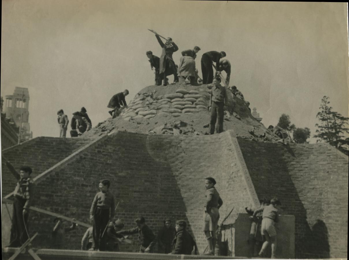 Madrid, 30 de marzo de 1939. Un grupo de niños retira la protección con la que se preservó la fuente de La Cibeles durante la Guerra Civil. 