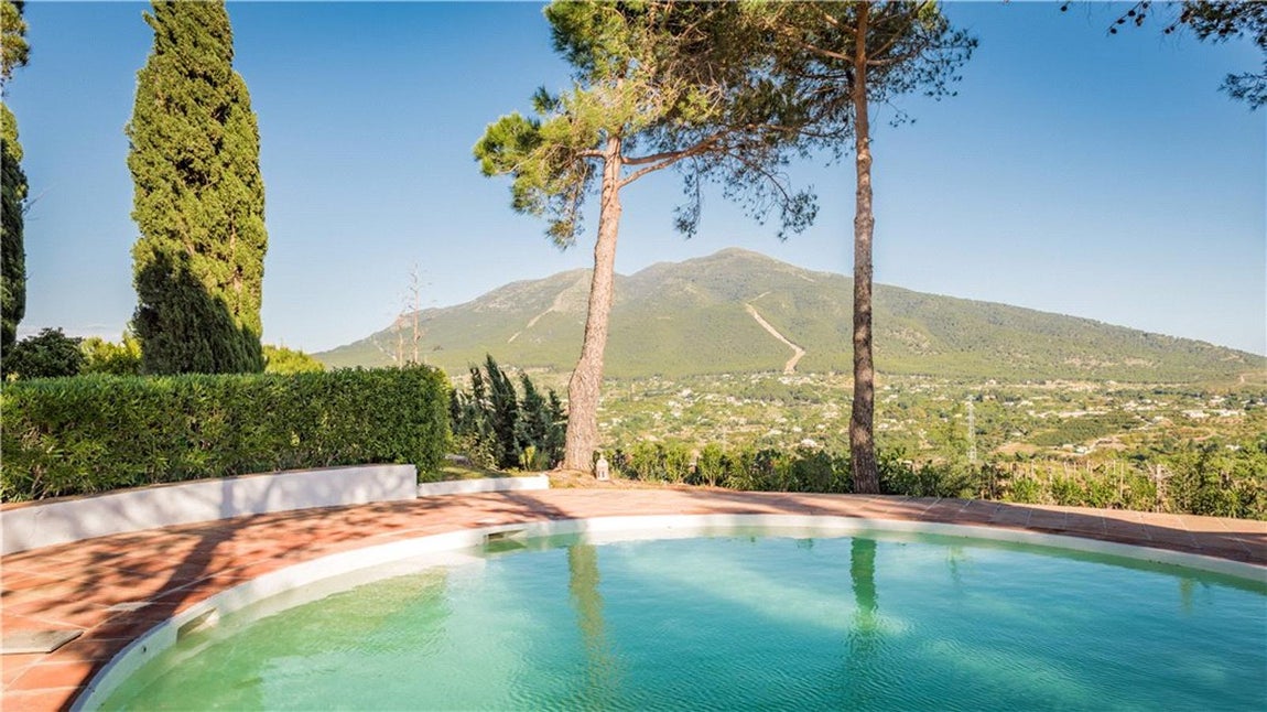 El maravilloso lugar, que se encuentra sobre una colina, tiene ocho habitaciones, las cuales 3 de ellas son suites, seis baños y un enorme jardín con una piscina. Además de tener unas bonitas terrazas, esta casa está repartida en casa principal y casa de huéspedes y hay personal distribuido por toda la parcela.