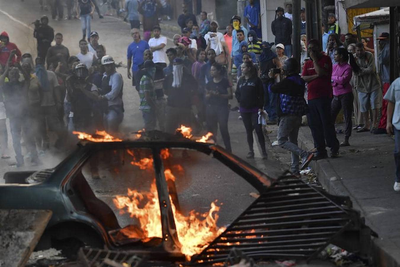 Las imágenes más dramáticas de la sublevación militar en Venezuela. En primer plano, un coche ardiendo; al fondo, manfestantes del barrio de Cotiza