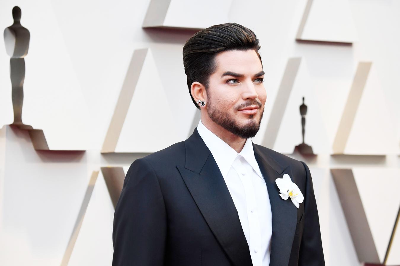 Adam Lambert. La estrella de «American Idol» que hizo de vocalista en la actuación de Queen, llevaba mangas XXL, flor de tela en el ojal de la chaqueta y camisa cerrada sin corbata