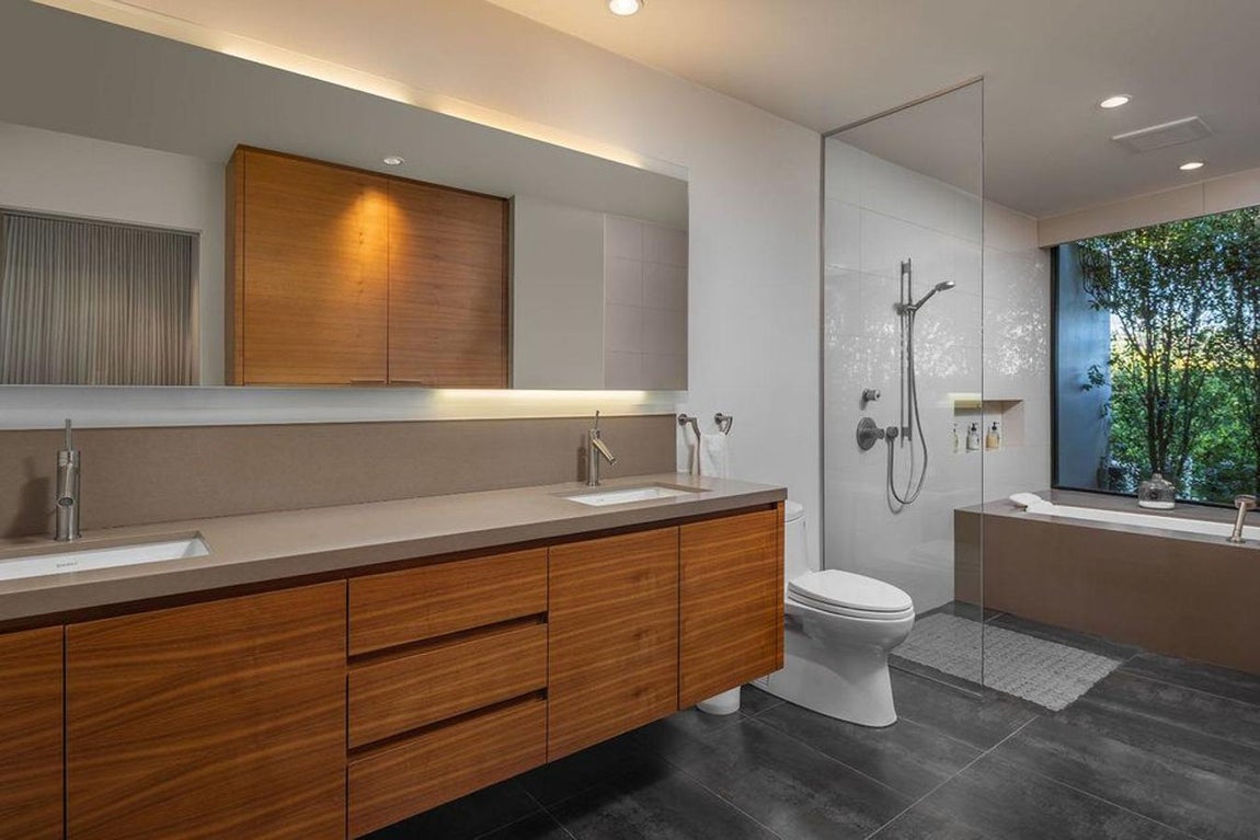 Baño. Los baños son espacioso, con muebles de madera y todos constan tanto de ducha como de bañera, en función de lo que más apetezca. Además, un gran ventanal, con vistas al jardín donde se puede apreciar el verde de la vegetación, se encuentra junto a la bañera