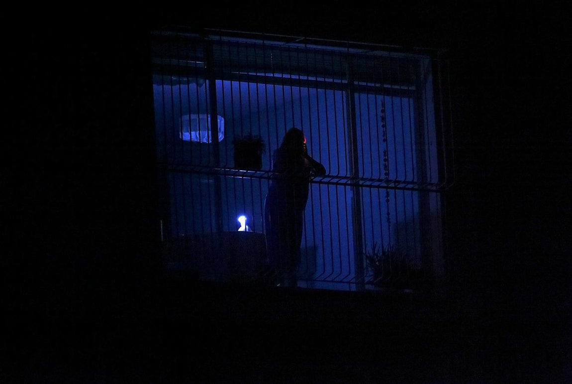Una mujer se asoma a una venana en una casa de Caracas, durante el nuevo apagón. 
