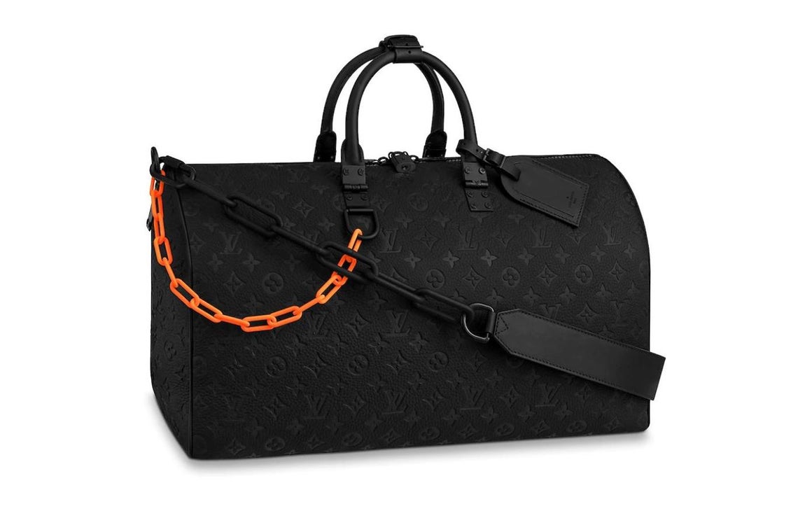 Keepall Bandouliere 50. La bolsa de vije se reinventa con la visión juvenil de Virgil Abloh, que ha añadido una serie de originales detalles al modelo. El motivo Monogram presenta una cadena en naranja mate para dar un toque urbano al conujunto, mientras que la bandolera de piel extraíble luce otra cadena en negro mate que acentúa aún más la estética contemporánea. Precio: 3.500 euros