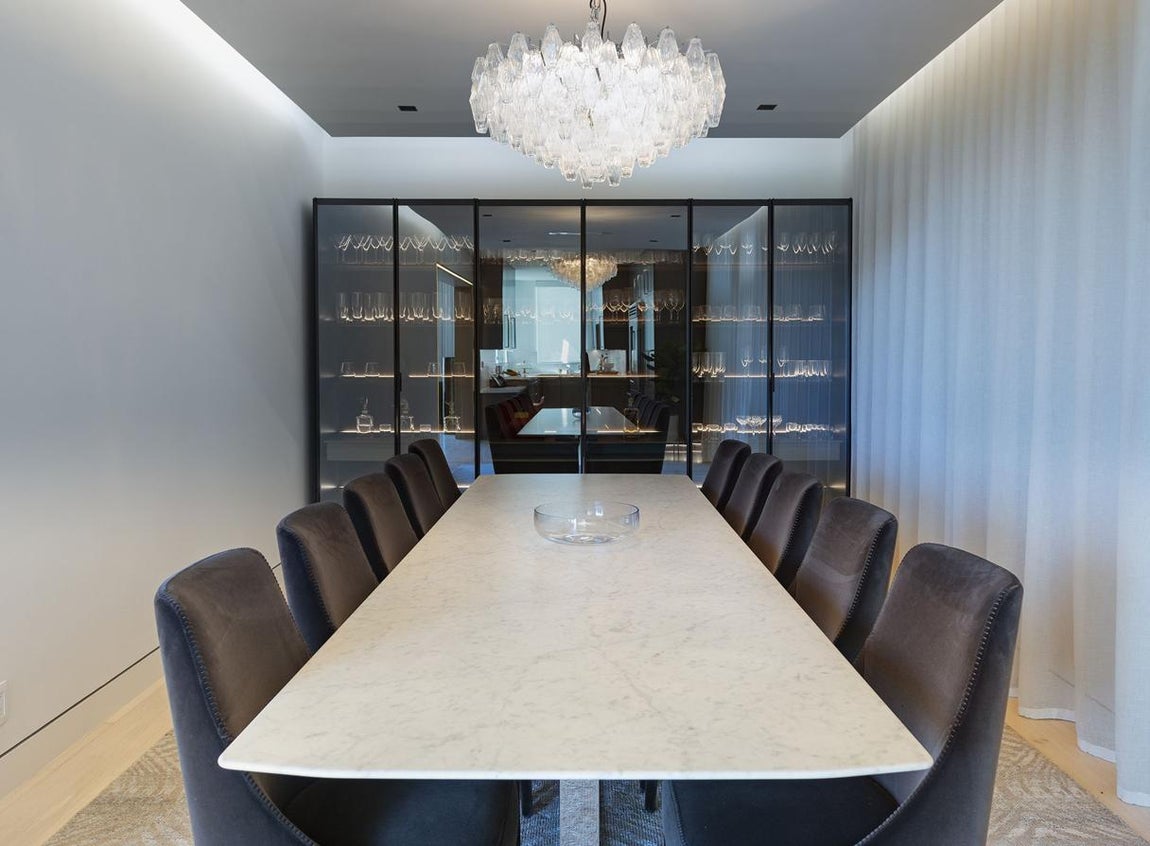 Comedor. Es una de las estancias más lujosas y elegantes de la casa. Con una enorme lámpara de araña como protagonista sobre una enorme mesa para 10 comensales y, al fondo, una sofisticada vitrina de cristal