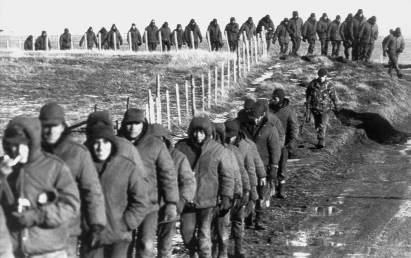 Los soldados argentinos (en primer plano) son escoltados por soldados británicos después de rendirse el 2 de junio de 1982 cerca de Goose Green, durante la Guerra de las Malvinas. 