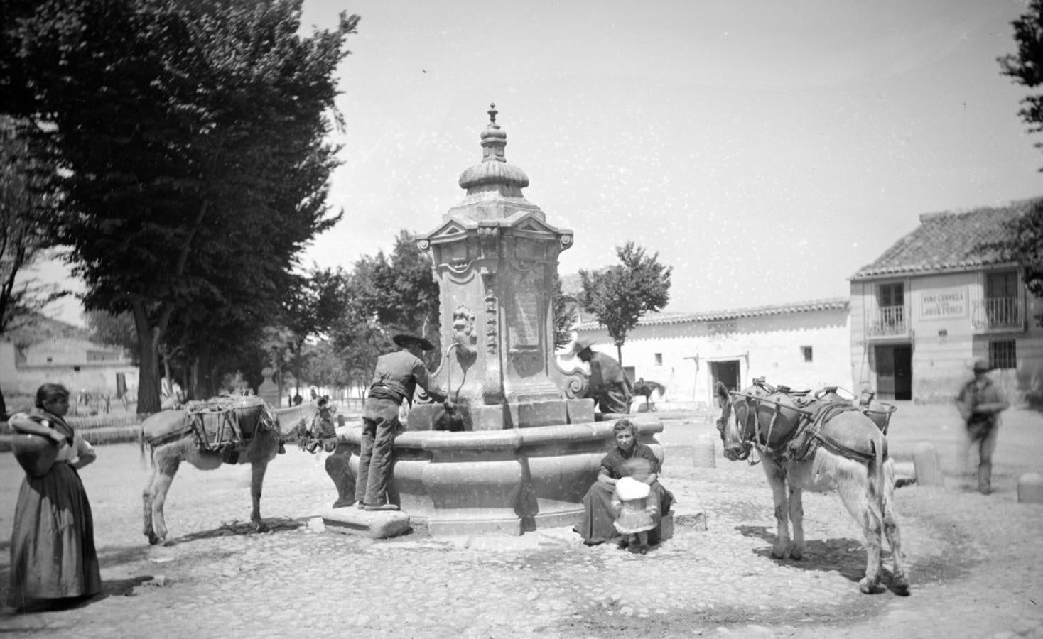 Escena en la fuente de Cabrahigos hacia 1890. Las casas del fondo se derribarían hacia 1911 al construirse la actual estación. Foto Alguacil. Archivo Municipal de Toledo. 