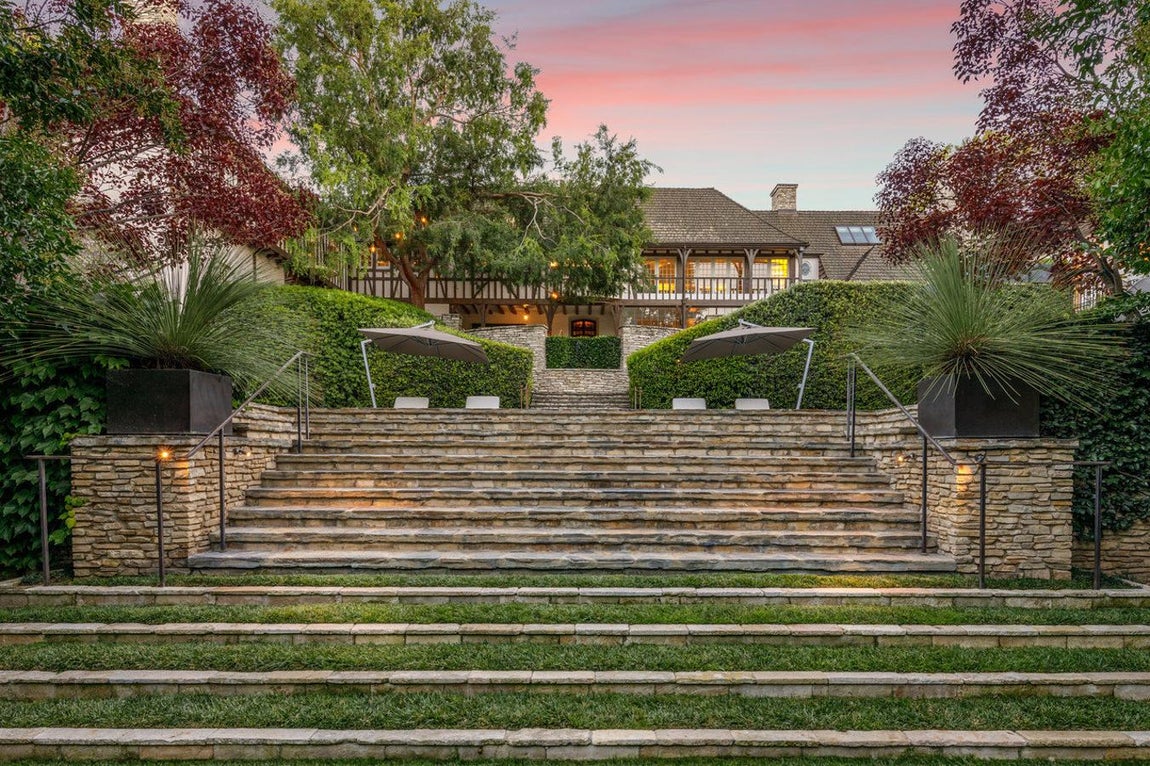 Patio de la vivienda. La vivienda está distribuida en distintos niveles y el jardín viene ser la parte más imponente de todas. Con numerosos escalones rodeados de césped, resulta agradable pensar en los días de verano disfrutando de las bonitas vistas que tiene la casa.