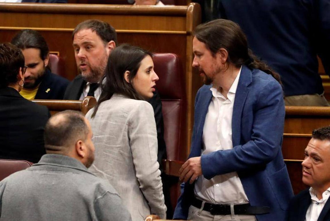 Irene Montero y Pablo Iglesias conversan junto a sus escaños. 