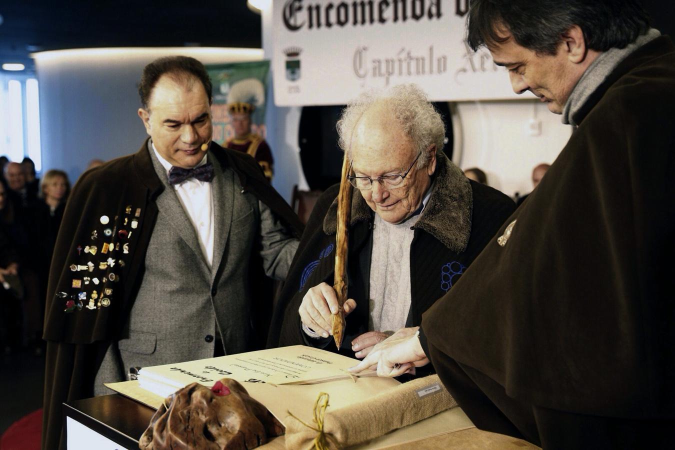 El escritor y divulgador científico Eduard Punset (c), firma en el libro de honor, tras ser nombrado nuevo comendador del Cocido de Lalín, municipio donde la versión gallega de este plato alcanza su máxima expresión.. 