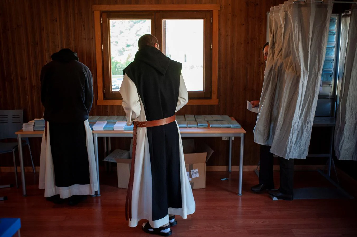 Dos monjes del Monasterio de Oseira escogen las papeletas para votar en la mesa electoral situada en esta localidad de San Cristovo de Cea. 