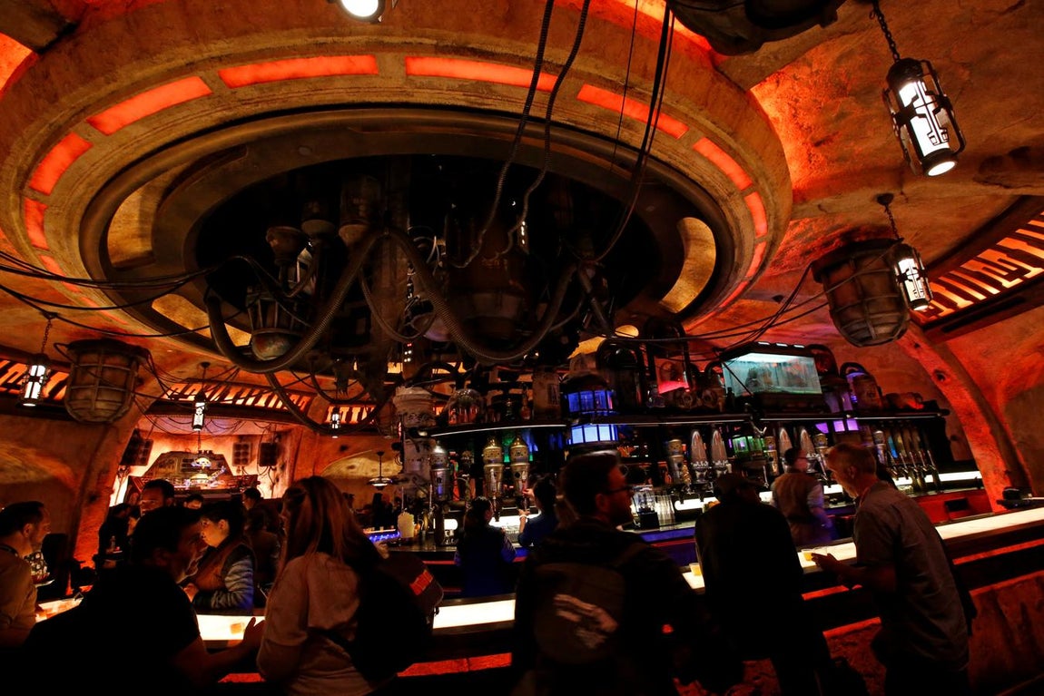 Zona de bares en Star Wars: Galaxy's Edge. Esta sección ofrecerá a los visitantes la posibilidad de subir a la cabina del Halcón Milenario y controlar un vuelo simulado. Los visitantes también podrán tomar leche azul, comer carne espacial asada por un motor de pod de repuesto y beber una copa en una cantina del espacio exterior.