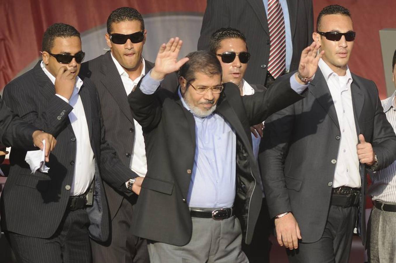 Flanqueado por guardaespaldas, el  que fuera presidente electo islamista de Egipto, Mohamed Mursi, saluda a los miles de egipcios a los que se dirigió en  la Plaza de Tahrir en El Cairo en 2012. 